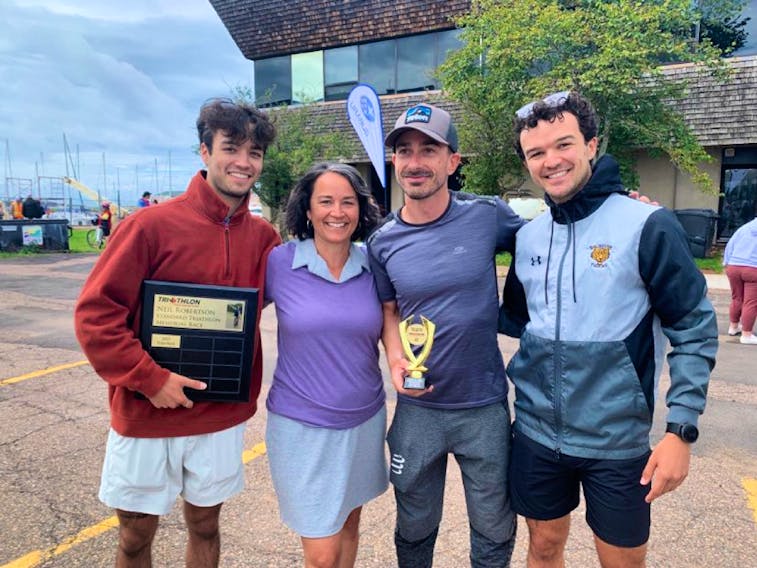 After Neil Robertson’s Standard Triathlon Memorial Race, Kathy Robertson gathered with her sons Nick, left, and Jesse, far right, to present Julien Buchart, centre right, with the award for first place in a world qualifying event. Contributed