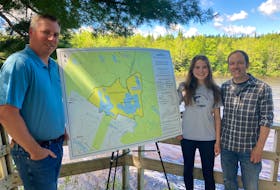 Gusborough-Tracadie MLA Greg Morrow, emcee Sadie Beaver and her father, St. Mary's River Association president Scott Beaver, unveil the Archibald Lake Wilderness Area at an event in Sherbrooke on Monday.