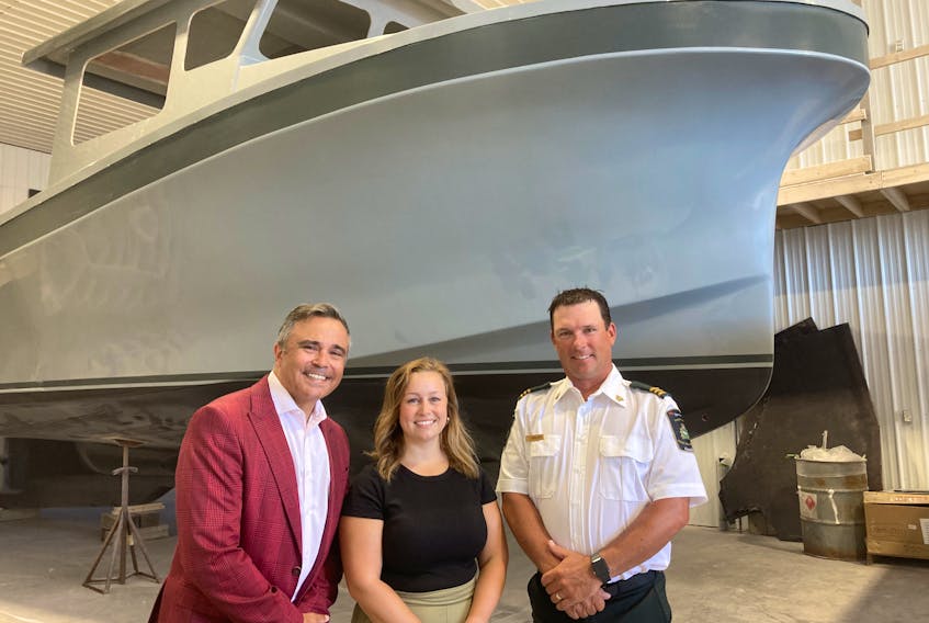 Cape Breton Canso MP Mike Kelloway, Rachelle Samson of Samson Enterprises and Scott Phillips, Fisheries and Oceans area chief, in front of one of the four new boats being built.