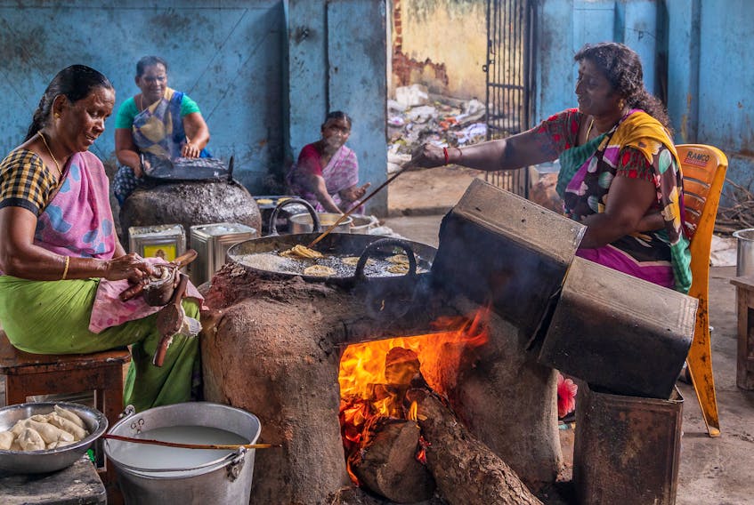 A photo of women in India working hard in the kitchen to craft traditional snacks. Louise Trotter