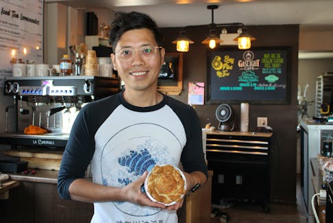 Seung Hyeon Park, who also goes by the English name Nathan, stands inside the Gaslight Cafe in Sydney holding one of their pot pies - a top seller at the eatery which Park owns with partner Bryden Mombourquette. NICOLE SULLIVAN/CAPE BRETON POST