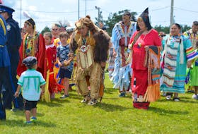 Elder Danny Paul wearing bear regalia interacts with an unidentified child during the powwow in Membertou on Sunday.