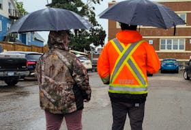 Two of the new security guards at the Community Outreach Centre in Charlottetown keep watch in the rain. - Logan MacLean • The Guardian