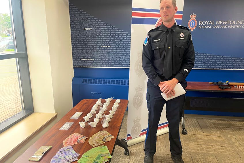 Royal Newfoundland Constabulary Const. James Cadigan stands next to some of the items seized by police when they executed a search warrant at a Merrymeeting Road home in St. John's this week, including cash, oxycodone pills and cocaine.