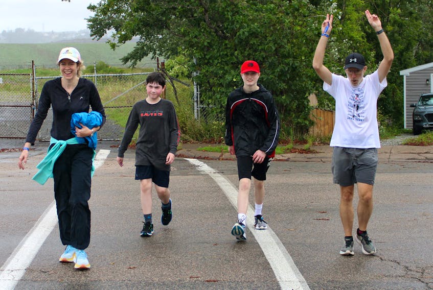 Steve MacNeil, right, raises his hands as he nears the end of the finish line during the Terry Fox Run in Sydney on Sunday. MacNeil has participated in every Terry Fox Run since the original Marathon of Hope took place in 1980. He is seen with Jennifer Weatherbee, from left, and her sons, Blake and Kyle Weatherbee. About 100 people took part in the Sydney run despite the rainy weather and organizers expected they would meet the $11,000 fundraising goal. Most of the nine other Terry Fox Run events in Cape Breton went ahead but a couple including the Glace Bay run were postponed until Sept. 24. CHRIS CONNORS/CAPE BRETON POST