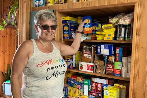 Carla Nickerson, a founding member and volunteer with the Villagedale Community Association, holds up a food product while standing in front of the cabinet in her kitchen that has served as a pantry for the association’s food security program since it was started last fall. KATHY JOHNSON
