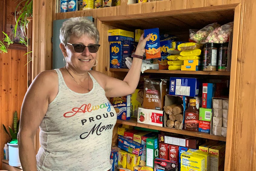 Carla Nickerson, a founding member and volunteer with the Villagedale Community Association, holds up a food product while standing in front of the cabinet in her kitchen that has served as a pantry for the association’s food security program since it was started last fall. KATHY JOHNSON