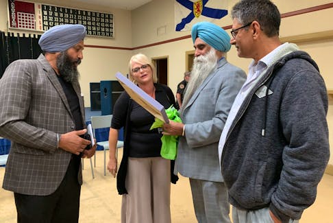 Barrington Passage business woman Lisa Marie Goodwin presented a folk-art painting of Charlesville done by local artist Anne Lovitt to the visiting Sikhs during a community meet and greet in Woods Harbour on Sept. 18. KATHY JOHNSON