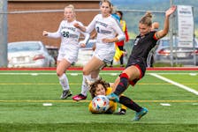 The UNB Reds’ Aurora Hughes-Goyette taps a ball past a diving UPEI keeper Claudia Mazzei during an Atlantic University Sport (AUS) Women’s Soccer Conference game in Fredericton, N.B., on Sept. 20. UPEI’s Olivia James, 26, and Roselyn Kushko, 3, follow the play. The Reds won the game 2-1. Fran Harris/For UNB Athletics • Special to The Guardian