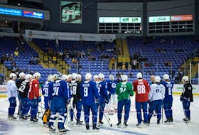 Vancouver Canucks players listen to head coach Rick Tocchet during the opening day of the NHL hockey team's training camp, in Victoria, Thursday, Sept. 21, 2023.