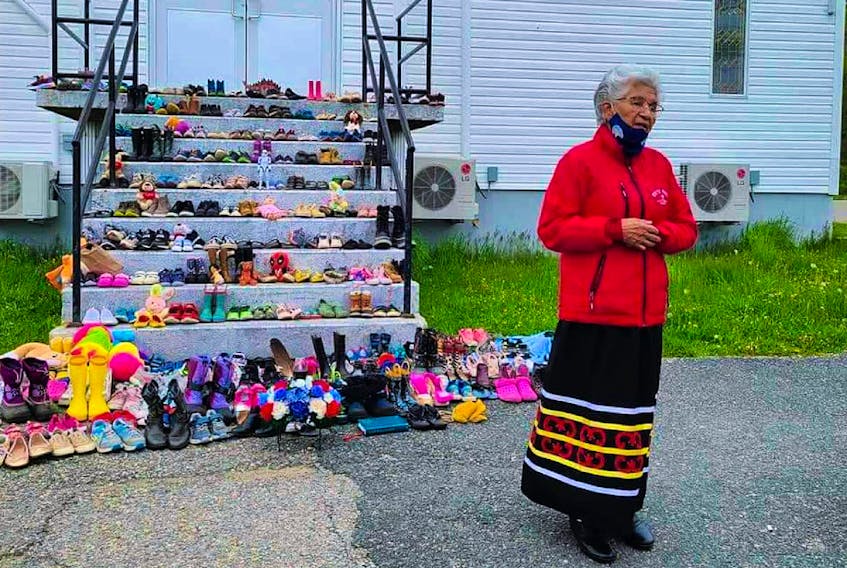 Georgina Doucette stands in front of Holy Family Catholic Parish church in Eskasoni. Each pair of shoes lining the entrance of the church symbolizes the missing and murdered Indigenous women and girls in Canada. - Contributed