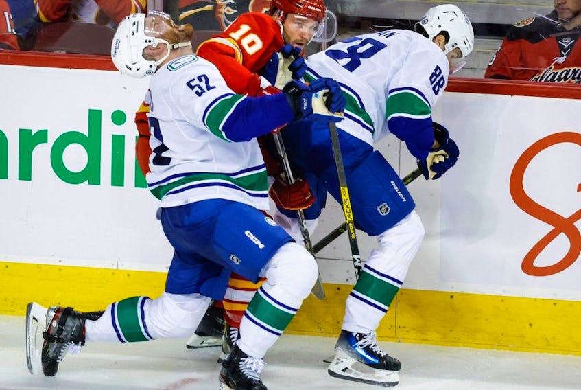 Vancouver Canucks' Matt Irwin, left, and Nils Aman check Calgary Flames forward Jonathan Huberdeau during NHL pre-season action in Calgary on Sept. 24.