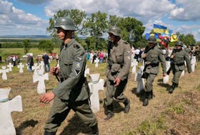 Ukrainians dressed in SS Galicia Division uniforms march past graves during a re-burial ceremony at the SS Galicia Division cemetery near the village of Chervone, Ukraine, in 2013.