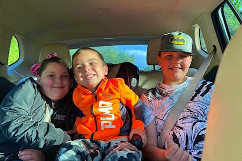 From left, Andrea MacLellan and her brothers Allister and Andy sit in the van that would transport them from Meat Cove to the school bus stop in Capstick on the first day of school in September 2022. The van transport is part of the school bus route from children from Meat Cove. CONTRIBUTED