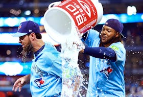 Brandon Belt of the Toronto Blue Jays ducks out of the way as Vladimir Guerrero Jr. tries to douse him with water.