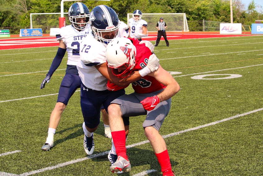 St. F.X. X-Men linebacker Dyton Blackett, centre, forces Acadia Axemen receiver Brady Newcomb out of bounds during Atlantic University Sport football action Sept. 2 in Wolfville.                  Blackett, a fifth-year X-Men from Canning, had five tackles and an interception.