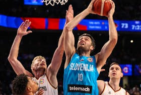 Mike Tobey of Slovenia drives to the basket against Niels Giffey and Johannes Voigtmann of Germany.