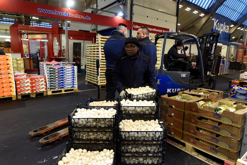A worker carries some mushrooms at the wholesale fruits and vegetables market in Hamburg Germany March 13, 2018.