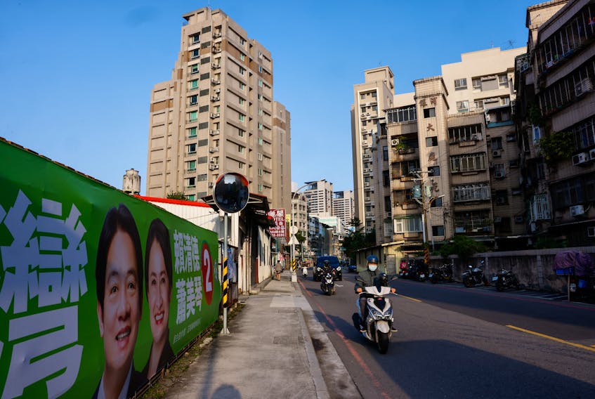 A person rides pass a campaign ad for Lai Ching-te, Taiwan's vice president and the ruling Democratic Progressive Party's (DPP) presidential candidate and Hsiao Bi-khim, the ruling Democratic Progressive Party's (DPP) vice presidential candidate ahead of the election in Taipei, Taiwan January 12, 2024.