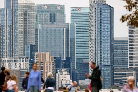 People stand at Greenwich Park, with the Canary Wharf financial district in the distance, in London, Britain, August 29, 2023.