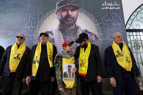 Hussein, son of Wissam Tawil, a commander of Hezbollah?s elite Radwan forces who, according to the group, was killed during an Israeli strike on south Lebanon, holds his picture at a memorial ceremony to mark one week since his killing, in Khirbet Silem, southern Lebanon, January 14, 2024.