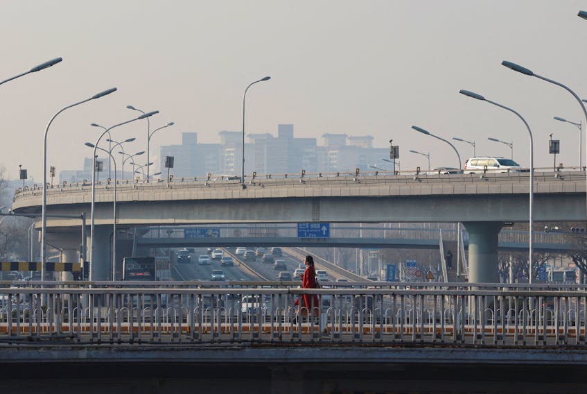 A pedestrian walks on an overpass past car traffic in Beijing, China January 12, 2024.