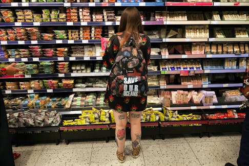 A person wearing a backpack with the slogan "SAVE OUR OCEANS", looks at food goods in a shop as UK inflation heads towards 10% in London, Britain, June 16, 2022.