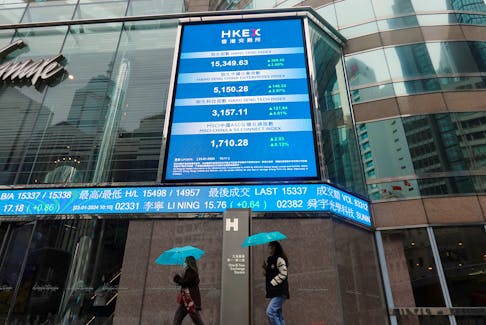 People walk past screens displaying the Hang Seng stock index and stock prices outside the Exchange Square in Hong Kong, China January 23, 2024.