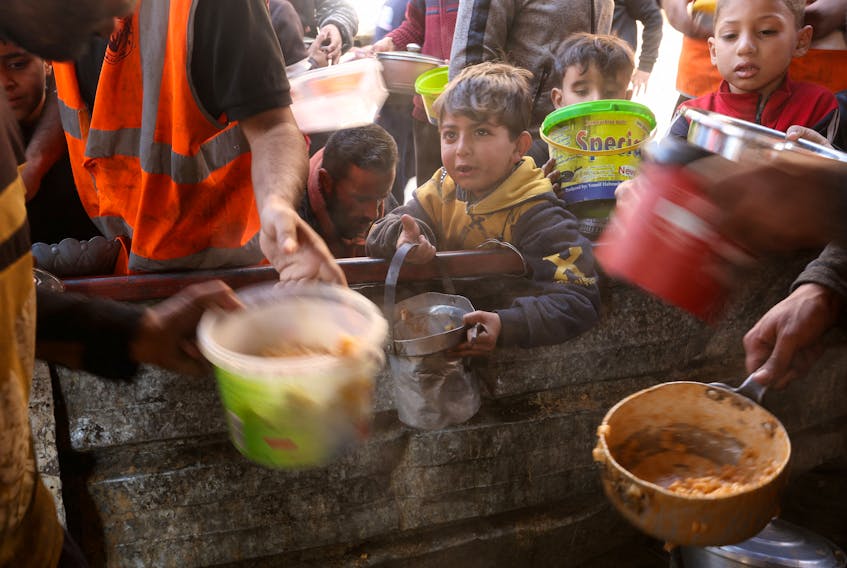 Palestinians wait to receive food cooked by a charity kitchen amid shortages of food supplies, amid the ongoing conflict between Israel and the Palestinian Islamist group Hamas, in Rafah in the southern Gaza Strip, January 16, 2024.