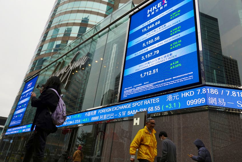 People walk past screens displaying the Hang Seng stock index and stock prices outside the Exchange Square in Hong Kong, China January 23, 2024.