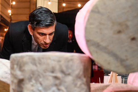 British Prime Minister Rishi Sunak looks at cheeses as he visits a food and drinks market promoting British small businesses over the festive season, on Downing Street in London, Britain, November 30, 2022.