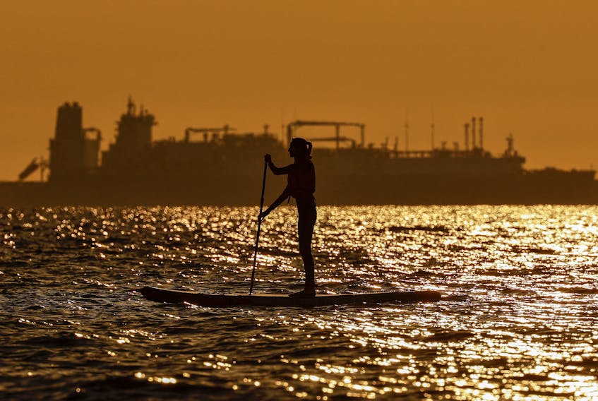 A paddleboarder rows in front of LNG carrier Marshal Vasilevskiy in the Baltic Sea resort of Zelenogradsk in the Kaliningrad region, Russia June 23, 2022.
