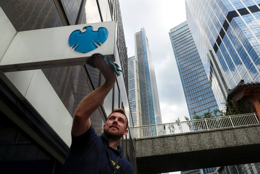 A worker cleans a Barclays logo outside a bank branch in the financial district of London, Britain July 8, 2019.
