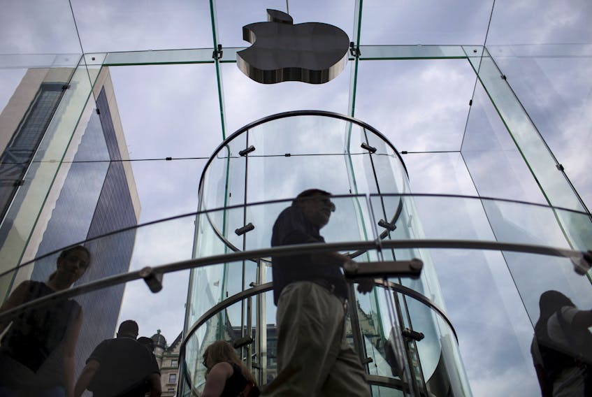 Customers enter the Apple store on 5th Avenue beneath an Apple logo in the Manhattan borough of New York City, July 21, 2015.