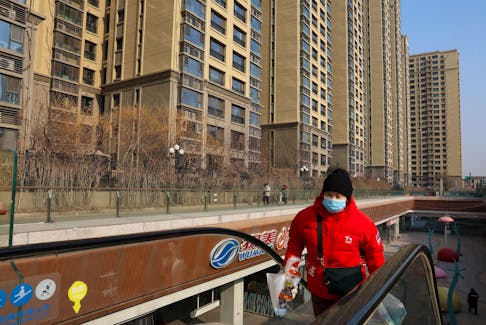A woman climbs an escalator near residential buildings next to the Evergrande City Plaza, after a court ordered the liquidation of property developer China Evergrande Group, in Beijing, China January 29, 2024.