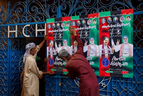 Workers hang campaign posters of a political party, ahead of general elections, in Karachi, Pakistan January 23, 2024.