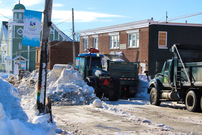 A snowplow blows snow into a dump truck bucket on Charlotte Street in Sydney on Saturday. By day's end, most of the street and its sidewalks were completely free of snow. LUKE DYMENT/CAPE BRETON POST