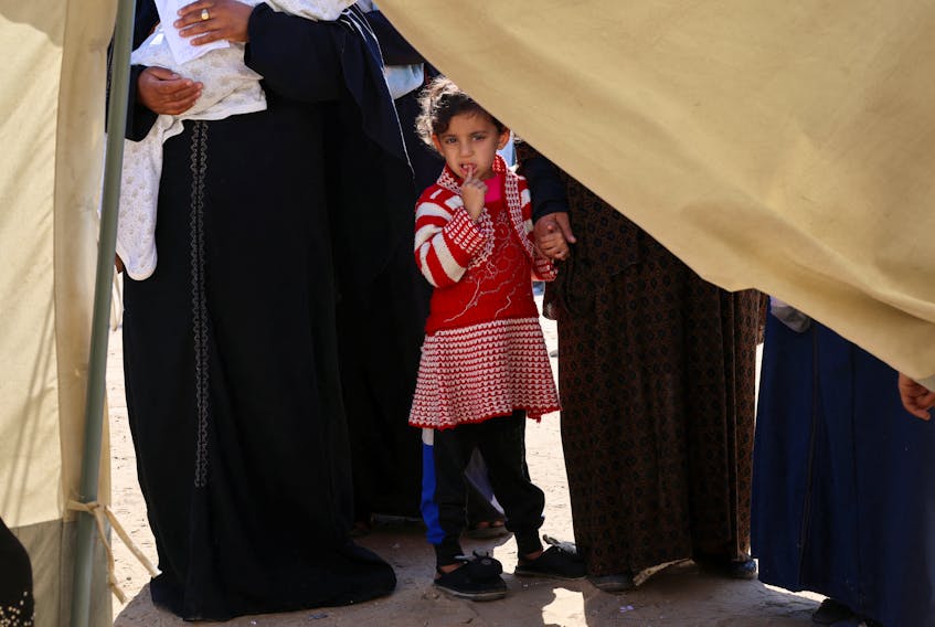 A displaced Palestinian girl holds her mother's hand as she waits to be examined by a doctor, outside a medical tent, amid the ongoing conflict between Israel and Hamas, in Rafah in the southern Gaza Strip February 11, 2024.