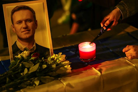 A person lights a candle next to a portrait of opposition leader Alexei Navalny as people attend a vigil in memory of Navalny in front of the Russian consulate at Europa square, in Munich, Germany, February 16, 2024.