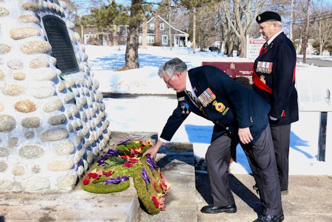 Darrell Leighton, the Royal Canadian Legion Hants County 009 branch president, lays a wreath during an outdoor service Feb. 19 recognizing the contributions of William Hall. Accompanying him to the cairn is sergeant-at-arms Charlie Lahey.