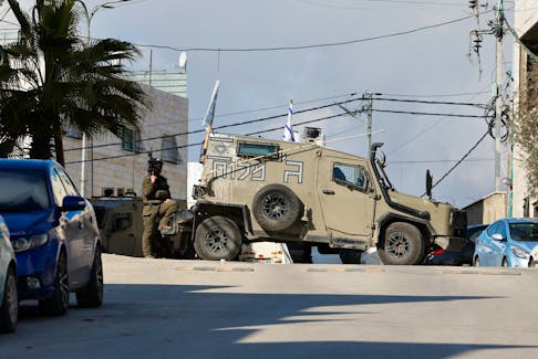 An Israeli soldier stands guard by a military vehicle, near a shooting scene in Hebron in the Israeli-occupied West Bank February 1, 2024.