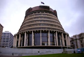 A pedestrian walks past the New Zealand parliament building known as the Beehive in central Wellington, New Zealand, July 3, 2017. 