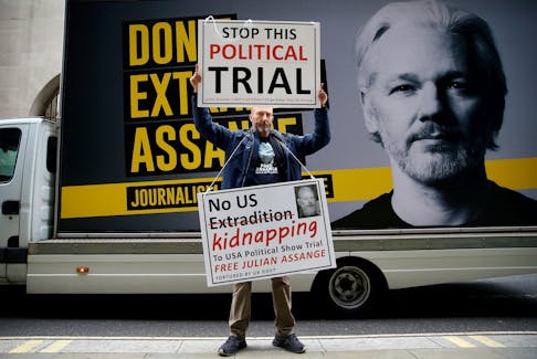 A protestor holds signs outside the Old Bailey, the Central Criminal Court ahead of a hearing to decide whether Assange should be extradited to the United States, in London, Britain September 8, 2020.