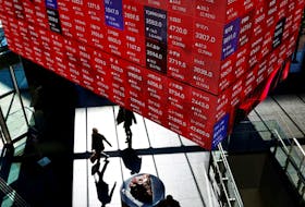 Visitors walk under Japan's Nikkei stock prices quotation board inside a building in Tokyo, Japan February 16, 2024. 