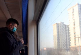 A passenger rides a train travelling past residential buildings during the Spring Festival travel rush on Lunar New Year's Eve, in Zhuozhou, Hebei province, China February 9, 2024.