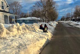 Greyson Anthony, 8, and his brother Jesse Anthony, 6, wait for the school bus on top of the snowbank on Tuesday, which has covered the sidewalk since the record-breaking snowfall earlier this month. The bus stop is on Atlantic Street in Sydney Mines and there isn't anywhere else for children who travel to school by bus to wait. CONTRIBUTED