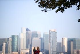 A woman holds a child in front of Canary Wharf skyline, in London, Britain September 14, 2020.