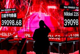 A visitor using his smartphone takes photos of an electronic screen displaying Japan's Nikkei share average, which surged past an all-time record high scaled in December 1989, inside a building in Tokyo, Japan February 22, 2024. 