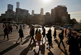 People cross a street during morning rush hour in front of the skyline of the central business district (CBD) in Beijing, China December 15, 2020.