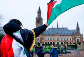 A man waves a Palestinian flag as people protest on the day of a public hearing held by The International Court of Justice (ICJ) to allow parties to give their views on the legal consequences of Israel's occupation of Palestinian territories before eventually issuing a non-binding legal opinion, in The Hague, Netherlands, February 21, 2024.